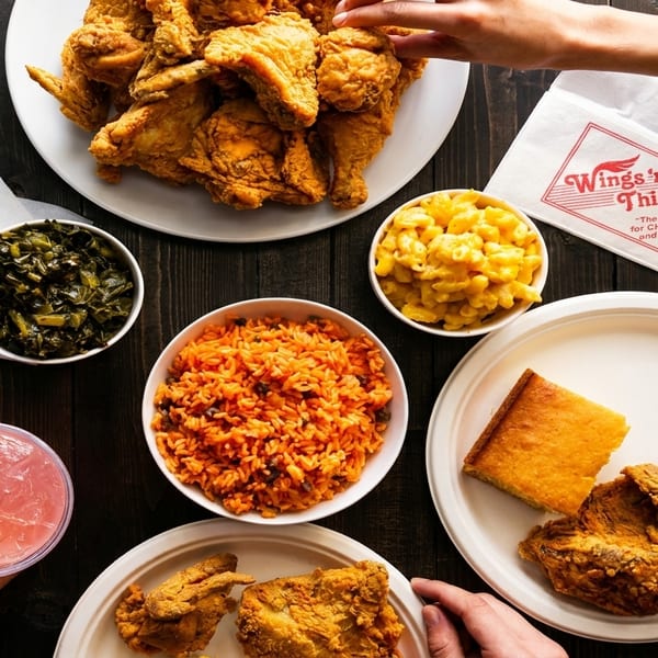 Overhead view of Wings 'n Things fried chicken, sides, and drinks on a dark wooden table.