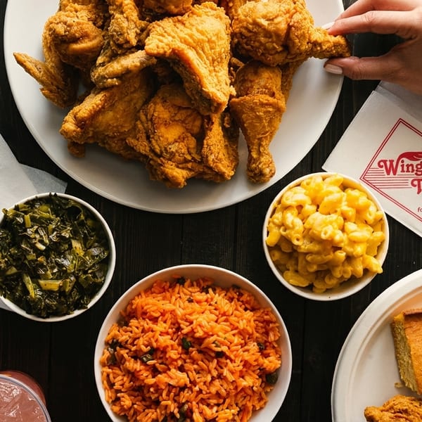 A spread of Wings 'n Things fried chicken, mac and cheese, collard greens, rice, cornbread, and a drink.